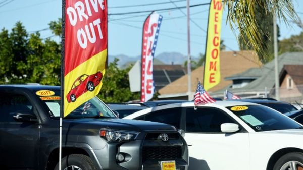 Used car lot with signs that read “drive out,” sale,” and “welcome”